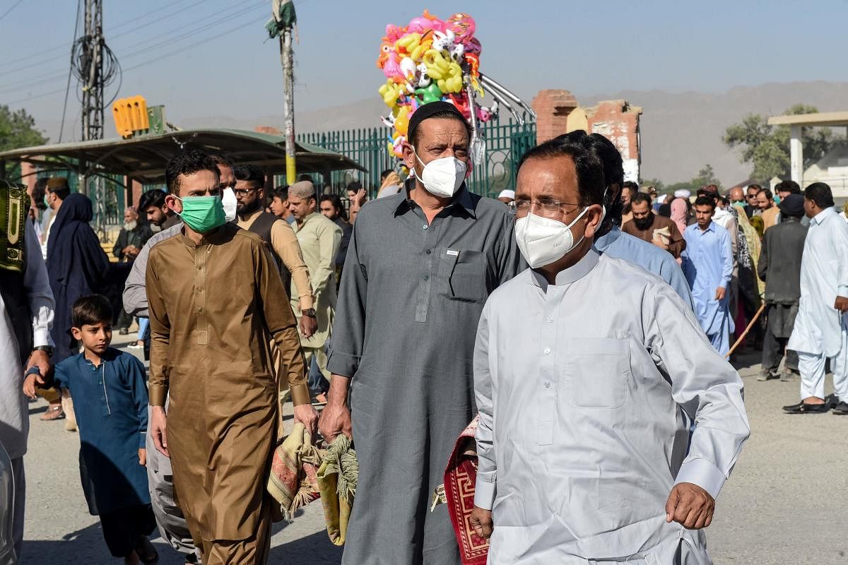 Muslims wearing facemasks come out after offering Eid al-Fitr prayers marking the end of the Muslim holy month of Ramadan at a ground in Quetta. (AFP Photo)