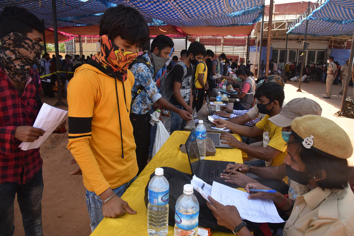 Migrant workers wait for passes to board the Shramik train on Sunday. DH Photo/S K Dinesh