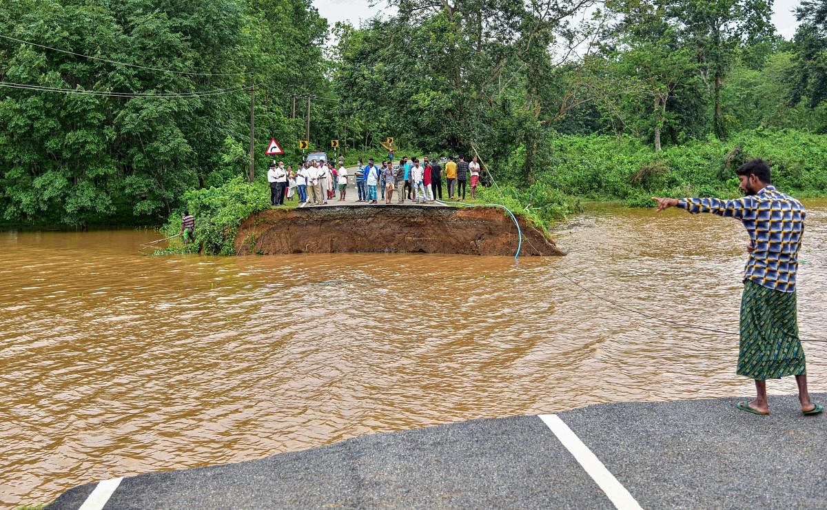 Villagers watch the part of a road that was washed away due to floods following heavy rainfall in Goalpara district of Assam. (PTI Photo)