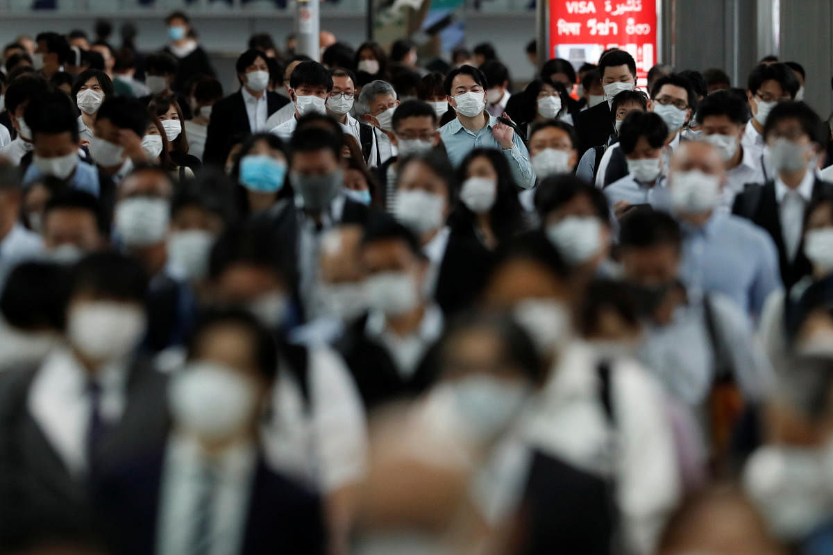 People wearing protective masks make their way during rush hour at Shinagawa station on the first day after the Japanese government lifted the state of emergency in Tokyo, Japan. (Reuters photo)