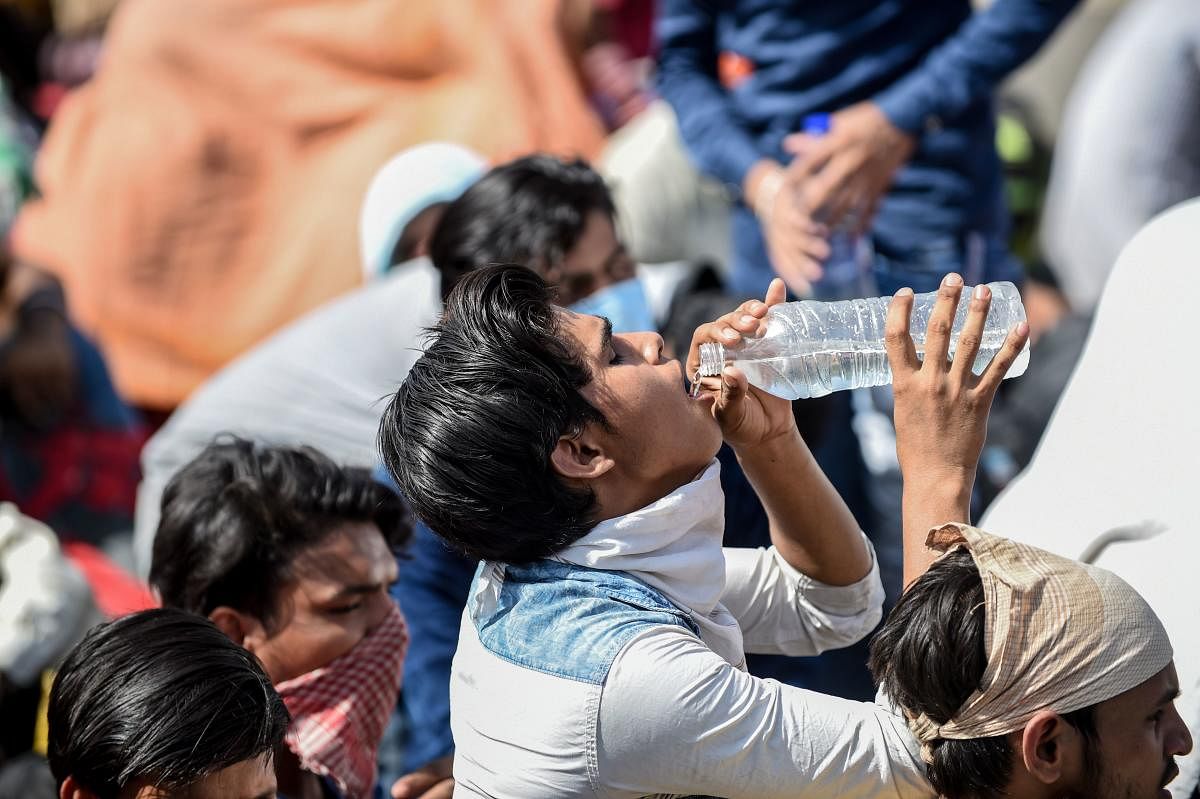 A man drinks water as he waits with other migrant workers and families for transportation going to the railway station to return by train to their hometowns. (Representative photo from AFP)