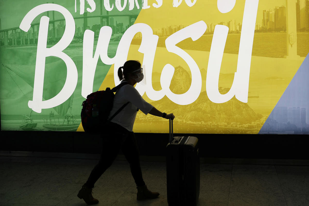 A traveller walks as she carries her bags at Guarulhos International Airport amid the outbreak of the coronavirus disease (COVID-19), in Guarulhos, near Sao Paulo. Reuters