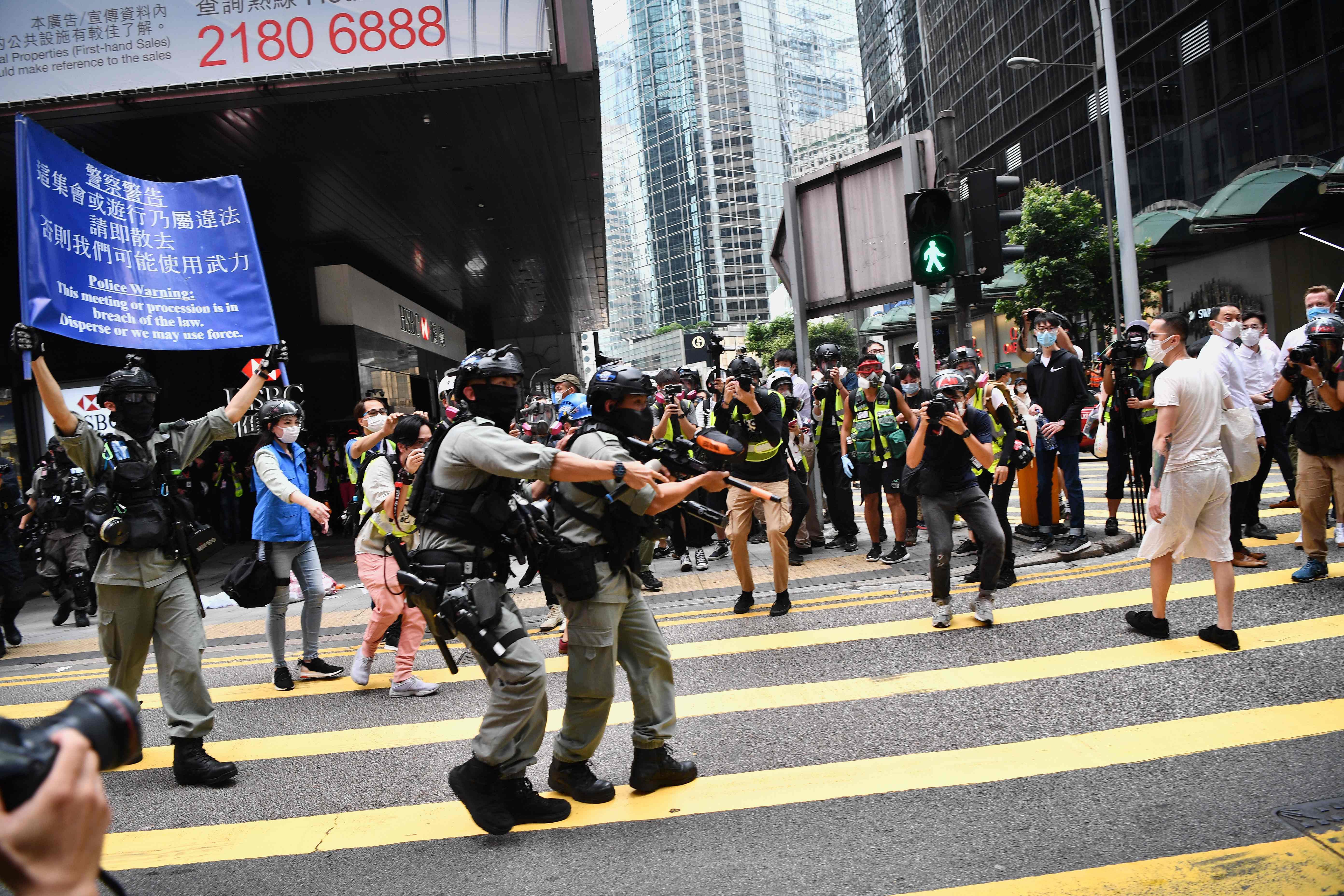 Hong Kong riot police (L) issue a warning as they plan to clear away people gathered in the Central district of downtown Hong Kong on May 27, 2020, as the city's legislature debates over a law that bans insulting China's national anthem. (AFP Photo)