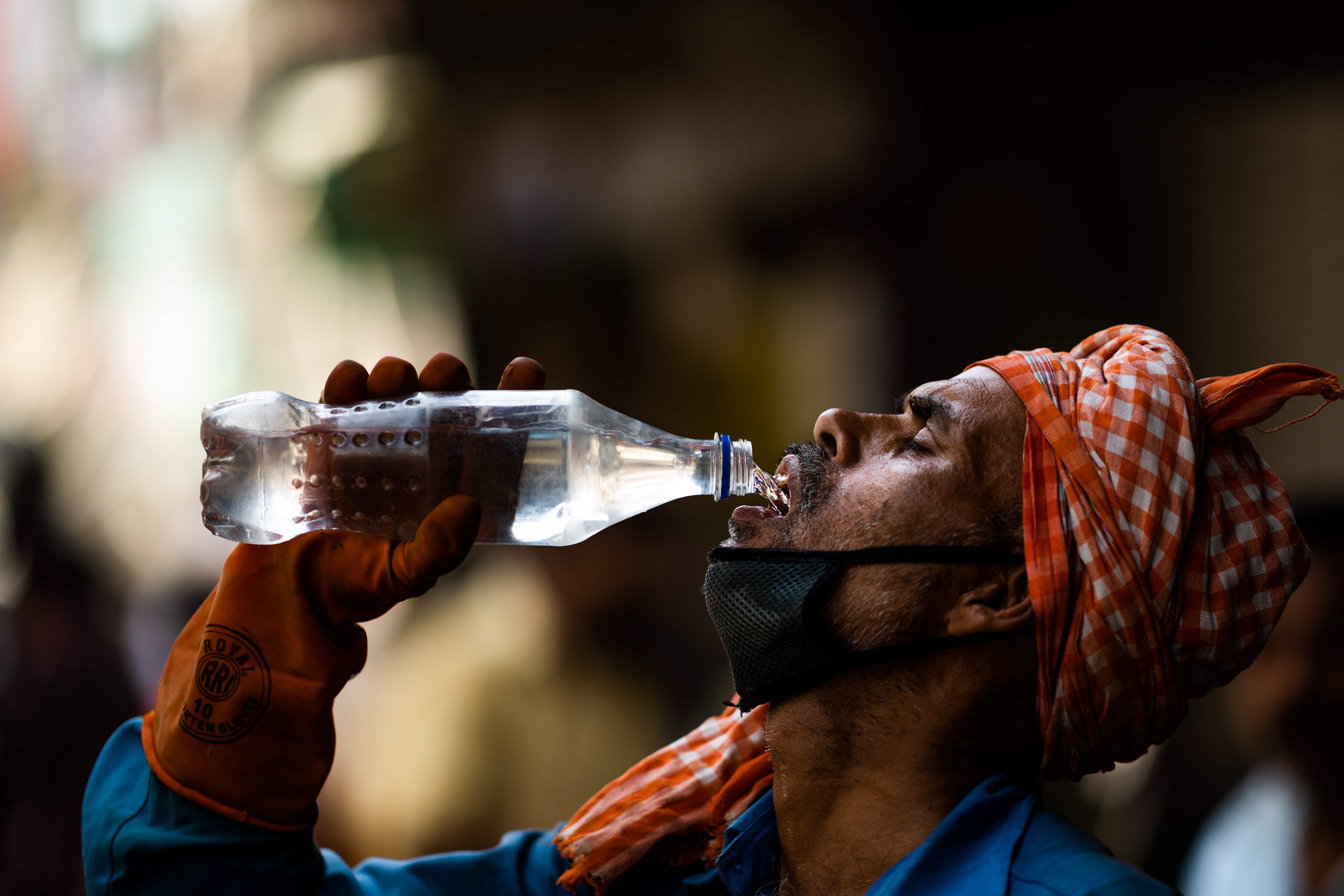 A labourer quenches his thirst with water from a bottle on a street amid rising temperatures in New Delhi. (AFP photo)