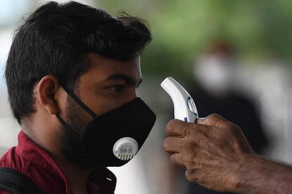 An airport staff checks the temperature of a passenger at the Kamaraj domestic airport during the first day of resuming of domestic flights after the government imposed a nationwide lockdown as a preventive measure against the spread of the COVID-19 coronavirus, in Chennai on May 25, 2020. (Credit: AFP Photo)