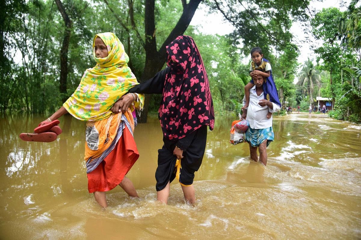  Villagers wade through a flooded area to reach a safer place after incessant rainfall at Bakulguri village, near Kampur in Nagaon District, Wednesday, May 27, 2020. (PTI Photo)