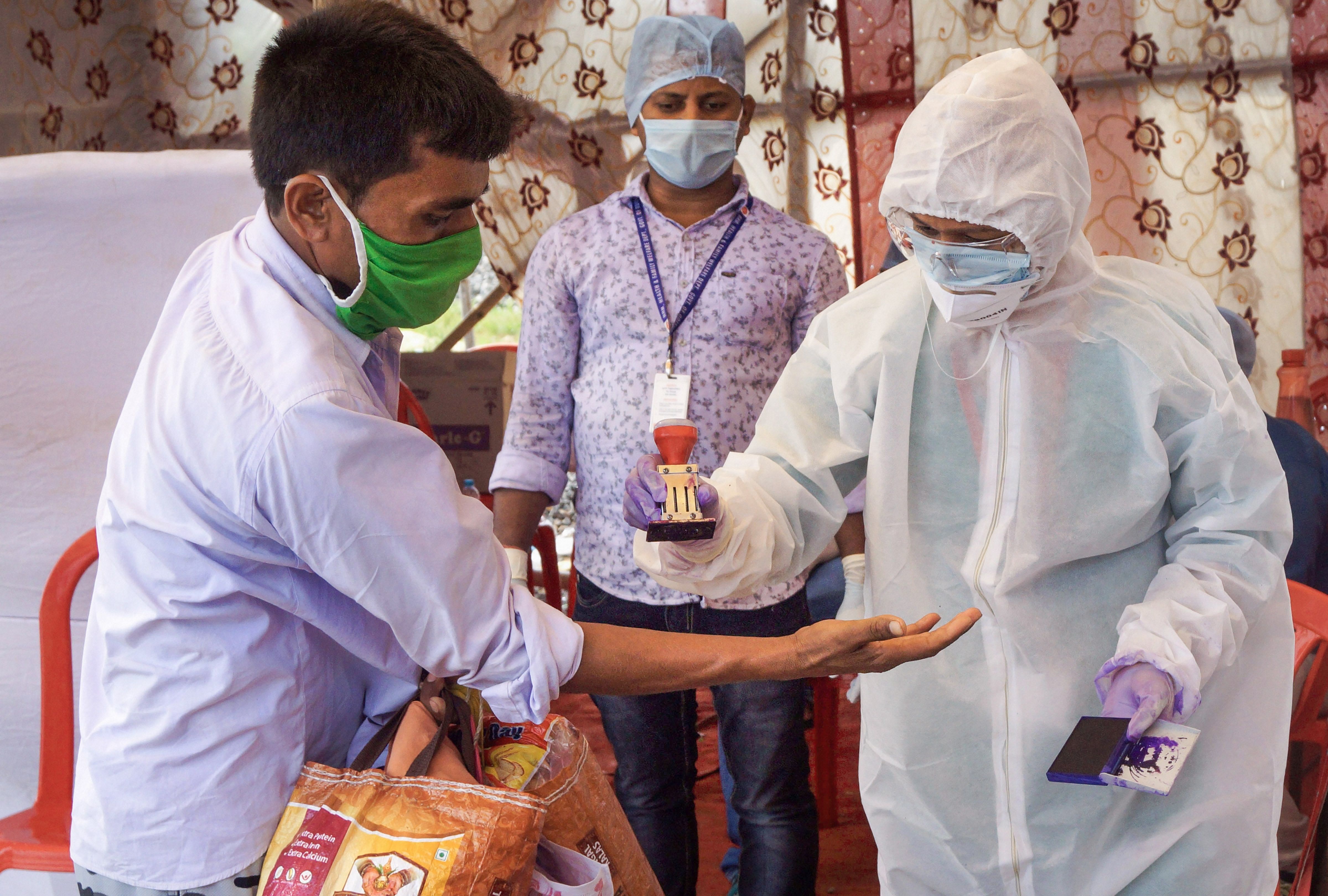 A migrant worker being marked with quarantine stamp by a medic after arriving to board a special train to his native home in Bihar at Bhubaneswar (New) railway station. (PTI Photo)