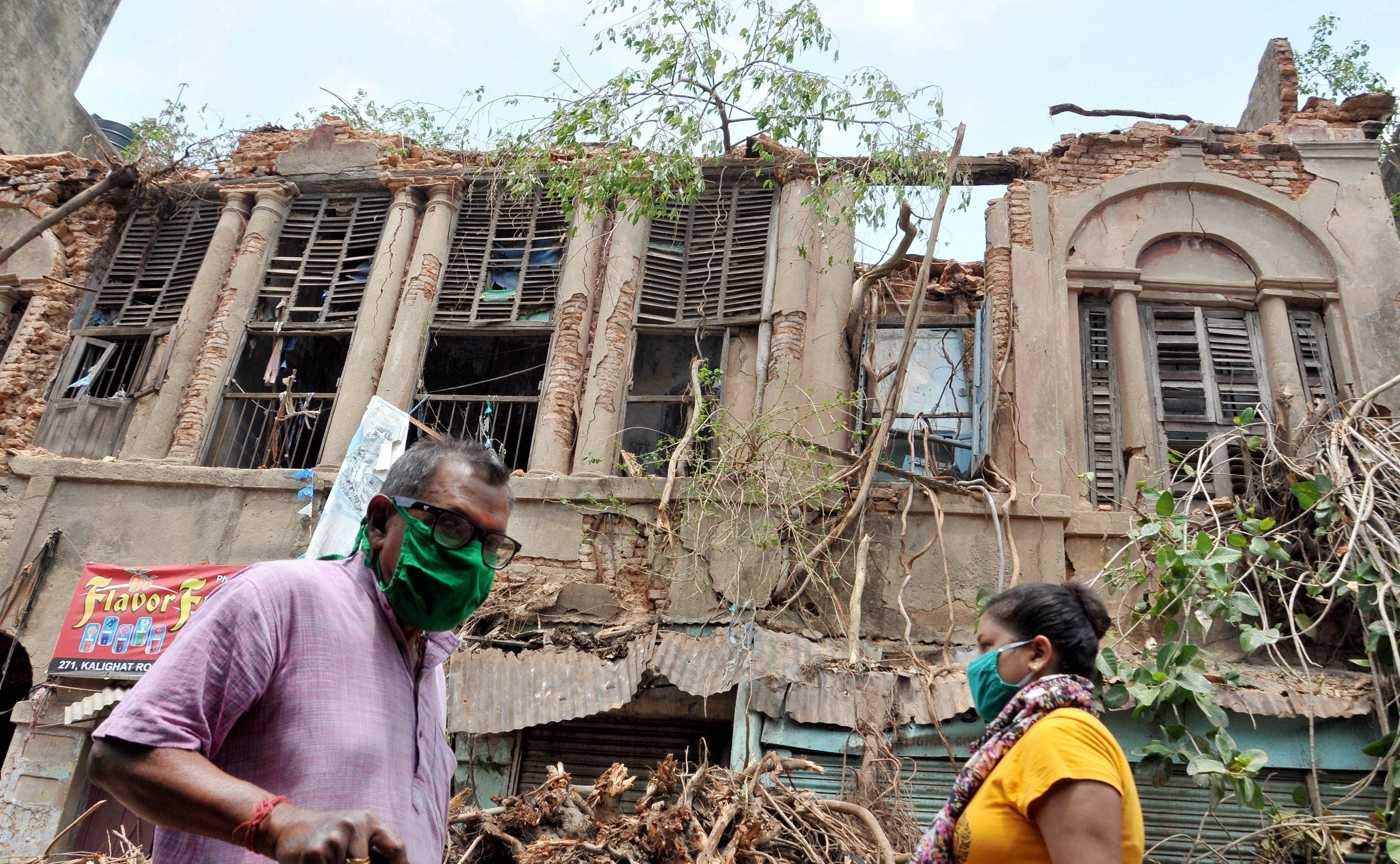 People walk past an abandoned house damaged during super cyclone Amphan, in Kolkata. (PTI photo)