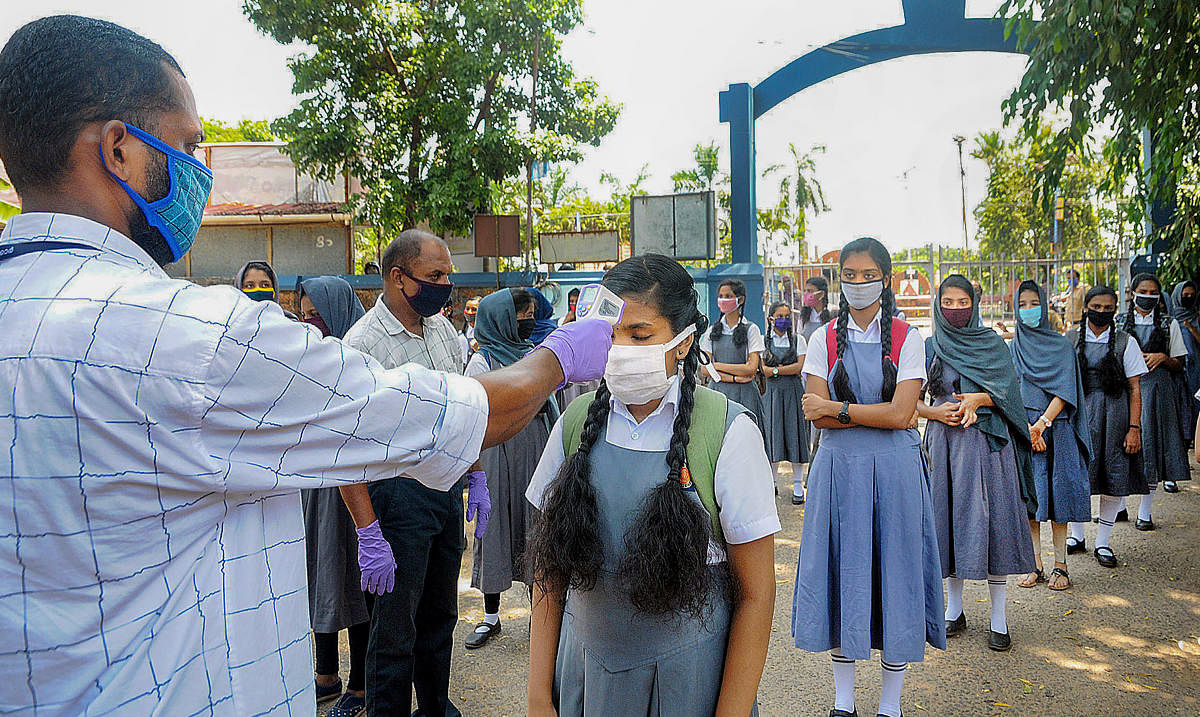 School staff screen students as they arrive to appear in the 10th examinations amid ongoing COVID-19 lockdown, in Kozhikode, Tuesday, May 26, 2020. (PTI Photo)