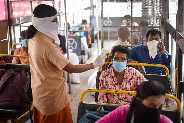  An APSRTC worker conducts thermal screening of a passenger at Pandit Nehru Bus Station, during the fourth phase of COVID-19 lockdown, in Vijayawada. (PTI Photo)