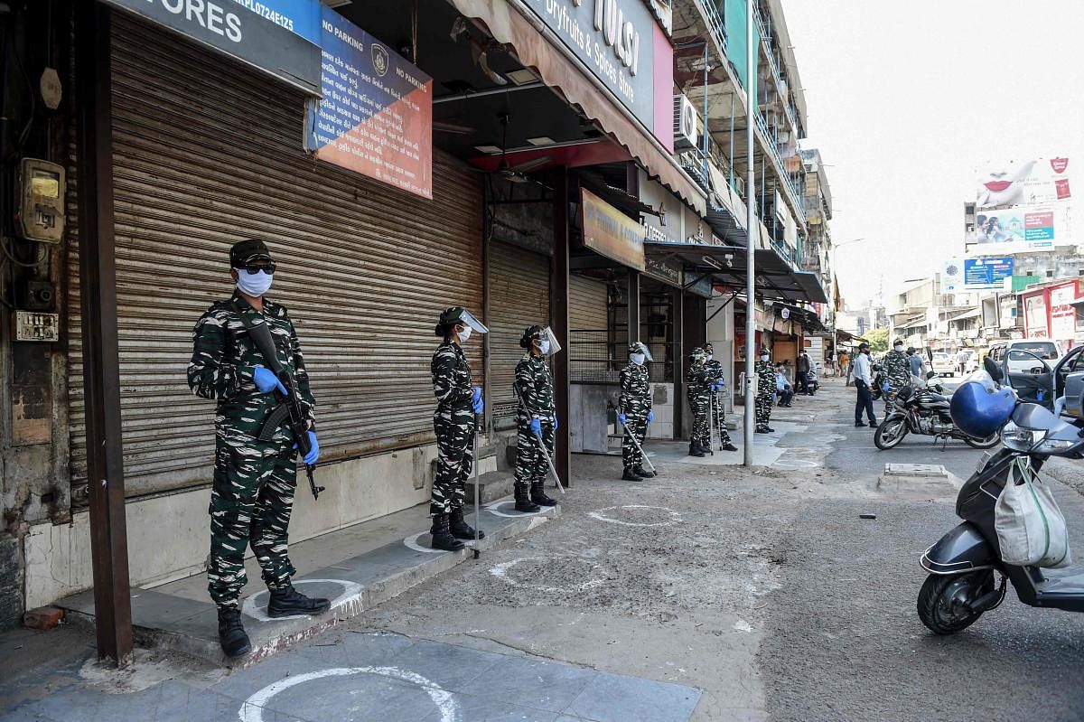 Security personnel stand guard outside shops closed by police personnel because customers were not maintaining social distancing after the government eased a lockdown imposed as a preventive measure against the COVID-19 coronavirus, in Ahmedabad on May 27, 2020. (Photo by SAM PANTHAKY / AFP)
