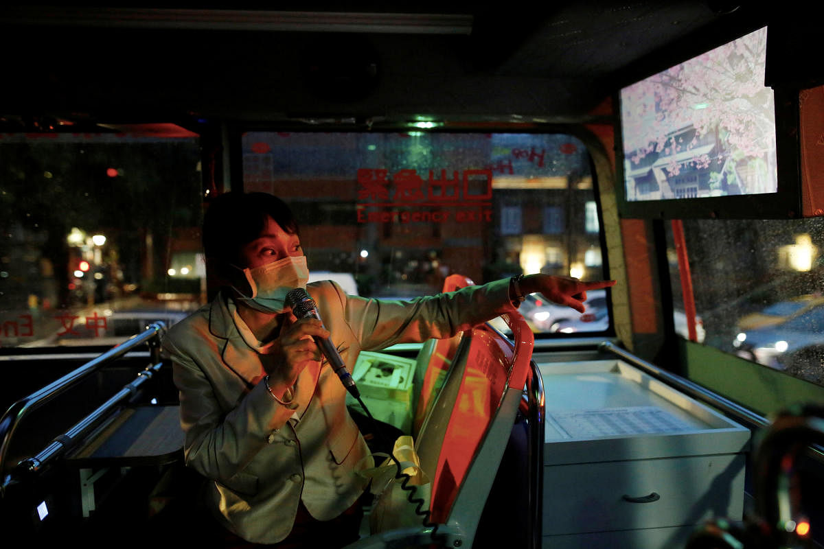 A tour guide speaks to a microphone while wearing a face mask to protect herself from the coronavirus disease (COVID-19) in an empty Taipei Sightseeing bus in Taipei. Reuters