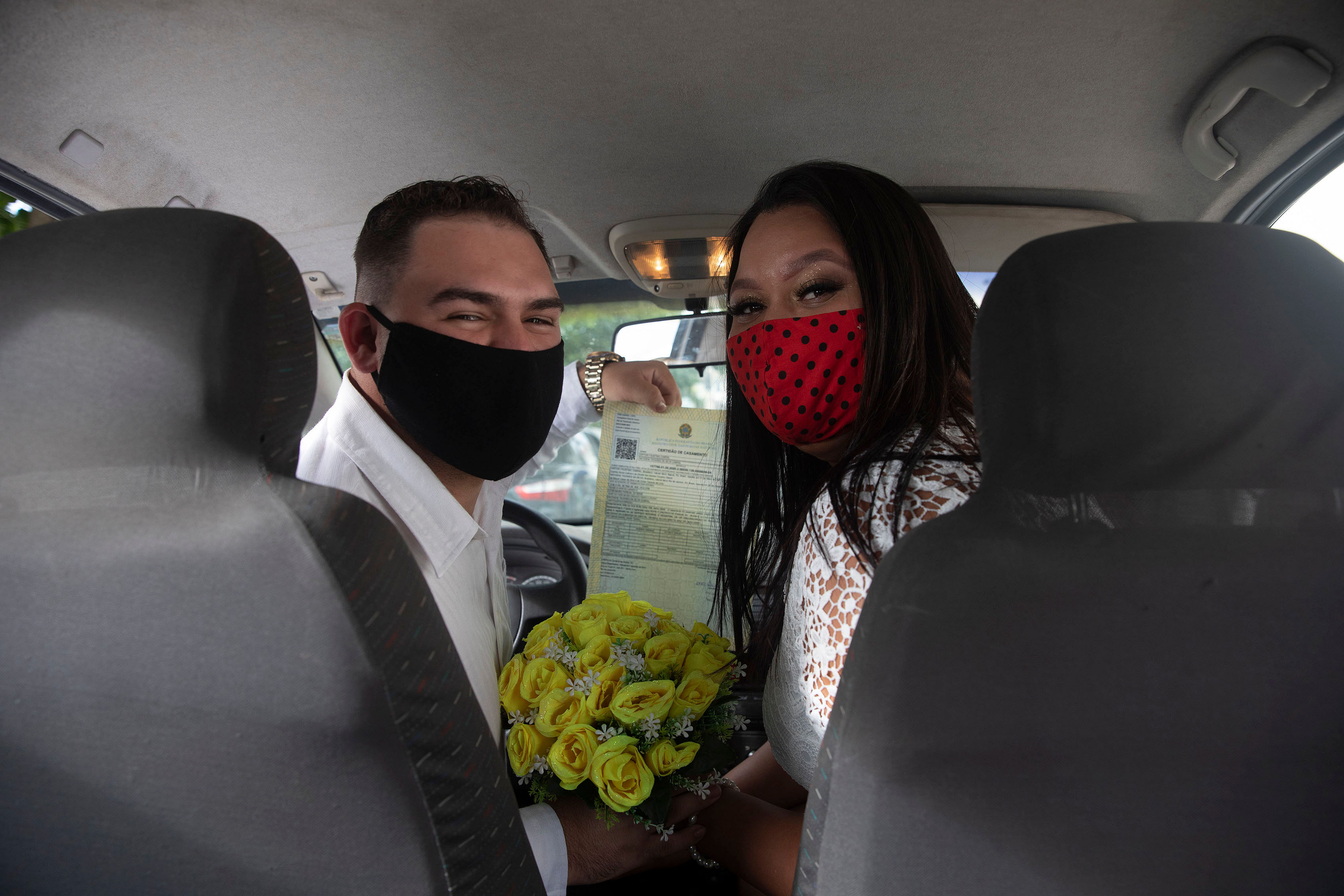 Ayrton, left, and Natasha, wearing masks to prevent the spread of the new coronavirus, pose for a photo after their drive-thru wedding at the registry office in the neighborhood of Santa Cruz in Rio de Janeiro, Brazil, Friday, May 22, 2020. Couples unable to have a traditional wedding because of the coronavirus pandemic are now taking part in drive-thru weddings. AP/PTI Photo