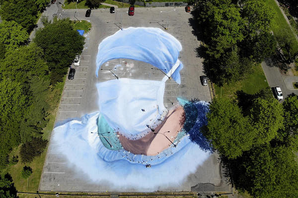 Artist Jorge Rodriguez-Gerada works on a 20,000 square foot mural of a health care worker in a parking lot in Flushing Meadows Corona Park in the Queens borough of New York, Wednesday,May. 27, 2020. (Credit: AP/PTI Photo)
