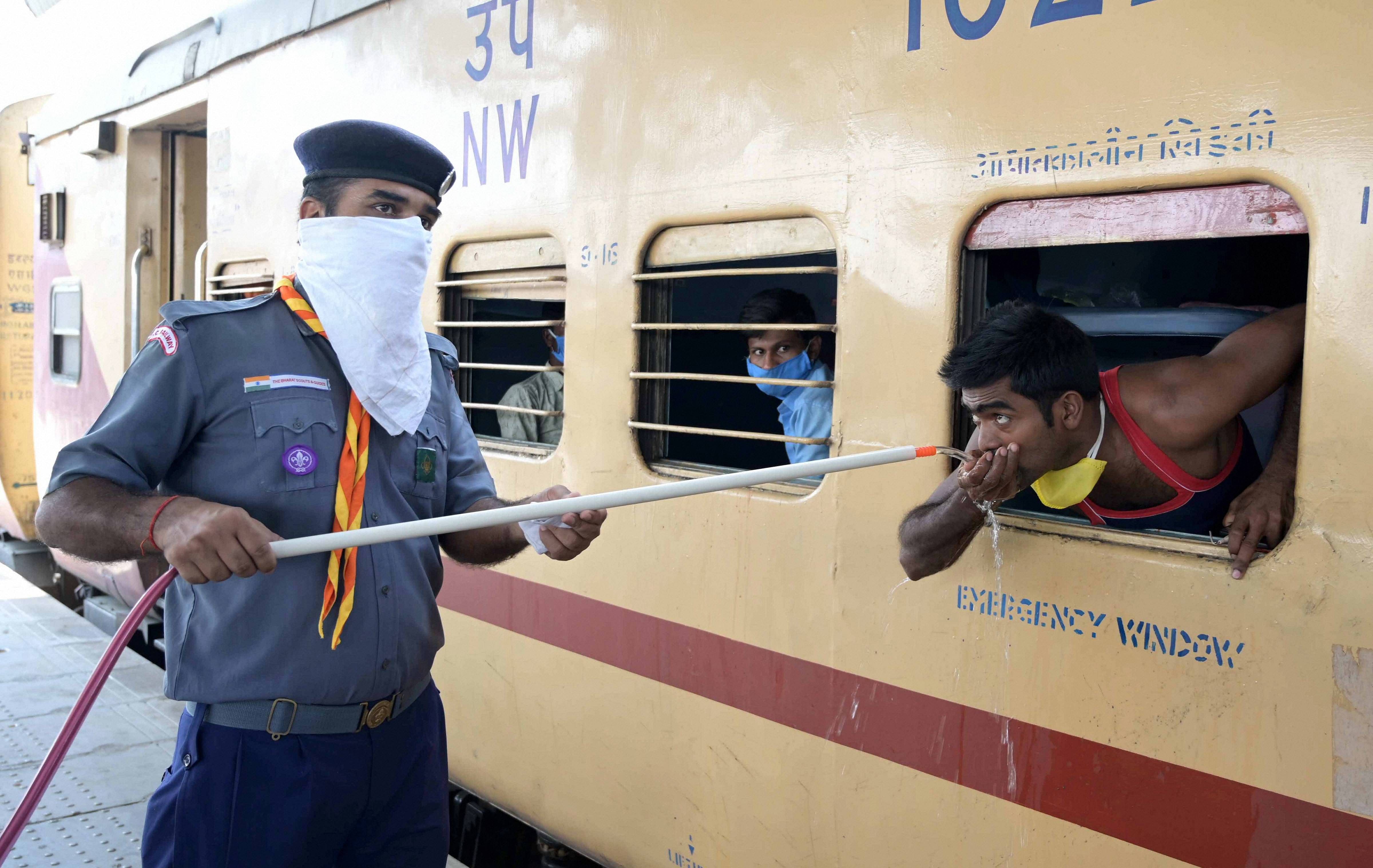  A cadet of Scouts & Guides provide drinking water to the migrants traveling in a Shramik Special train. (PTI Photo)