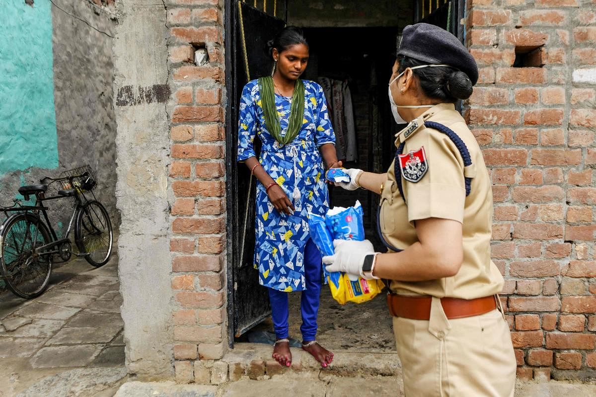 A Punjab police personnel distributes sanitary pads to residents during a government-imposed nationwide lockdown as a preventive measure against the COVID-19 coronavirus, in Amritsar. (PTI Photo)