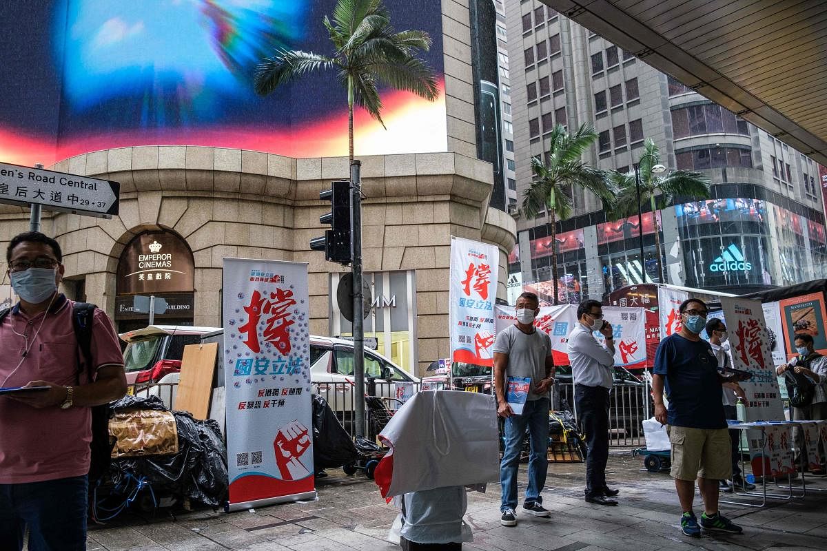 People stand at a booth where passersby can give their signatures in support of a new security law in Hong Kong on May 29, 2020. Credit: AFP Photo