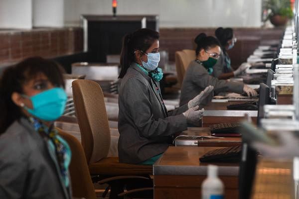 Airline staff work at their counters at the Chhatrapati Shivaji Maharaj International Airport (CSMIA) after domestic flights resumed, in Mumbai on May 28, 2020. (Credit: AFP Photo)