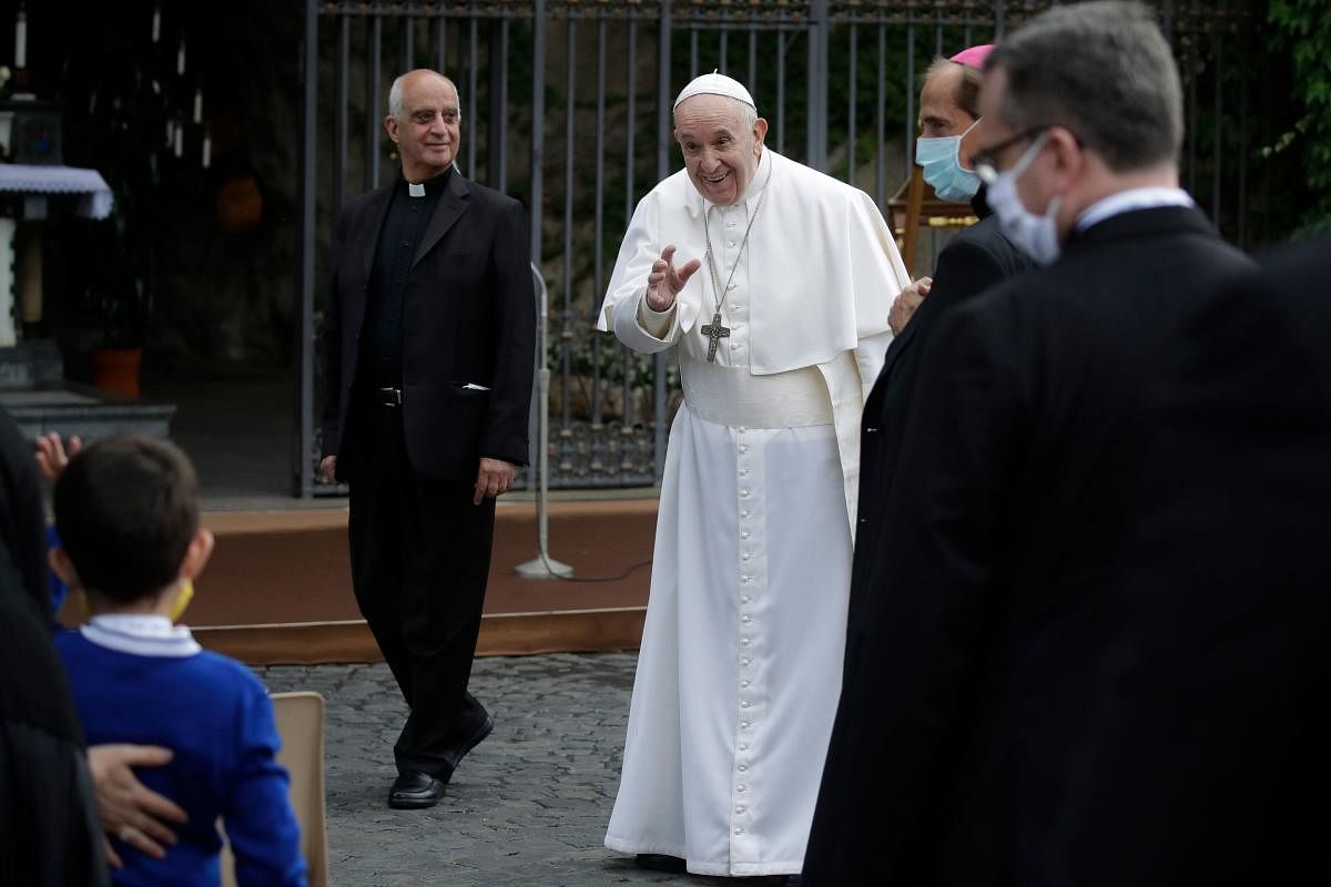 Pope Francis waves to a child as he leaves after a rosary in the Vatican gardens. AFP
