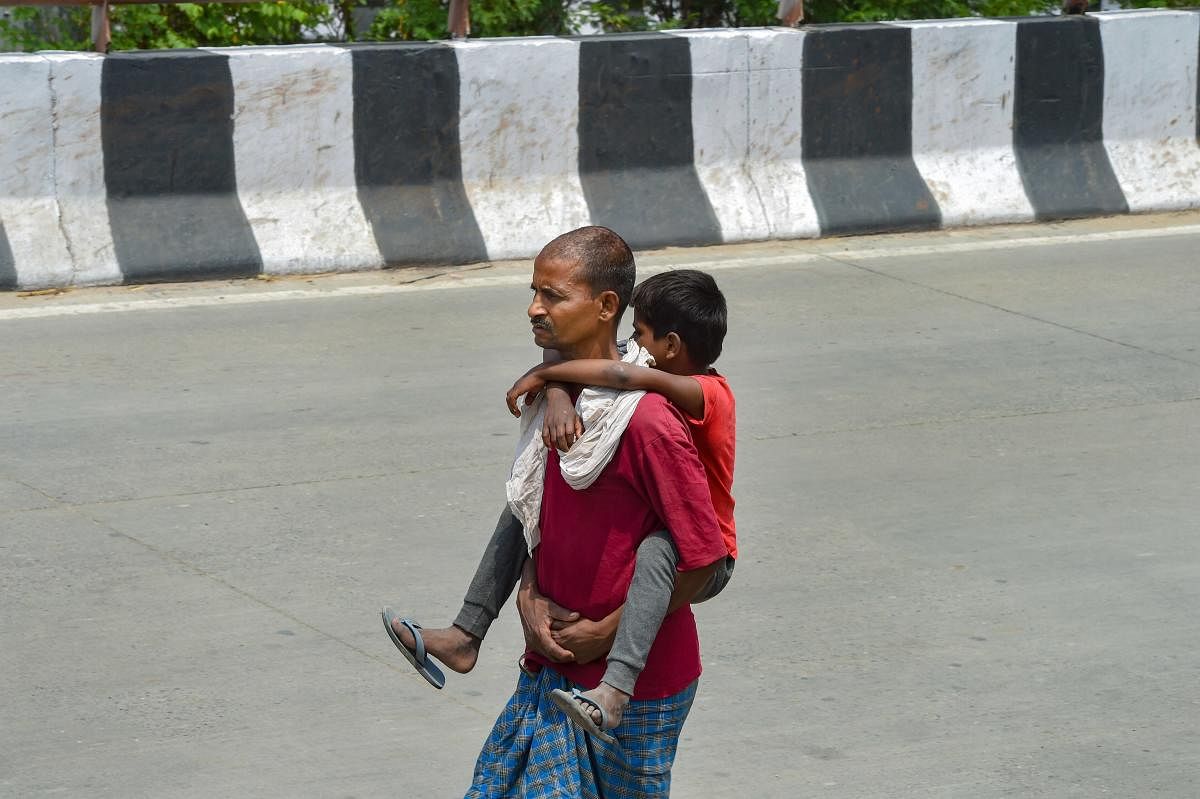 New Delhi: A migrant carrying his child walks along a road, during the ongoing COVID-19 nationwide lockdown, in New Delhi, Sunday, May 31, 2020. (PTI Photo/Shahbaz Khan)(PTI31-05-2020_000122B)