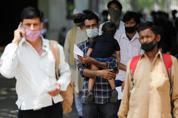  man carries his son as he stands with others in a queue at a Railway reservation ticket counter after a few restrictions were lifted during an extended nationwide lockdown to slow the spread of the coronavirus disease (COVID-19), in New Delhi, India, June 1, 2020. (Reuters Photo)