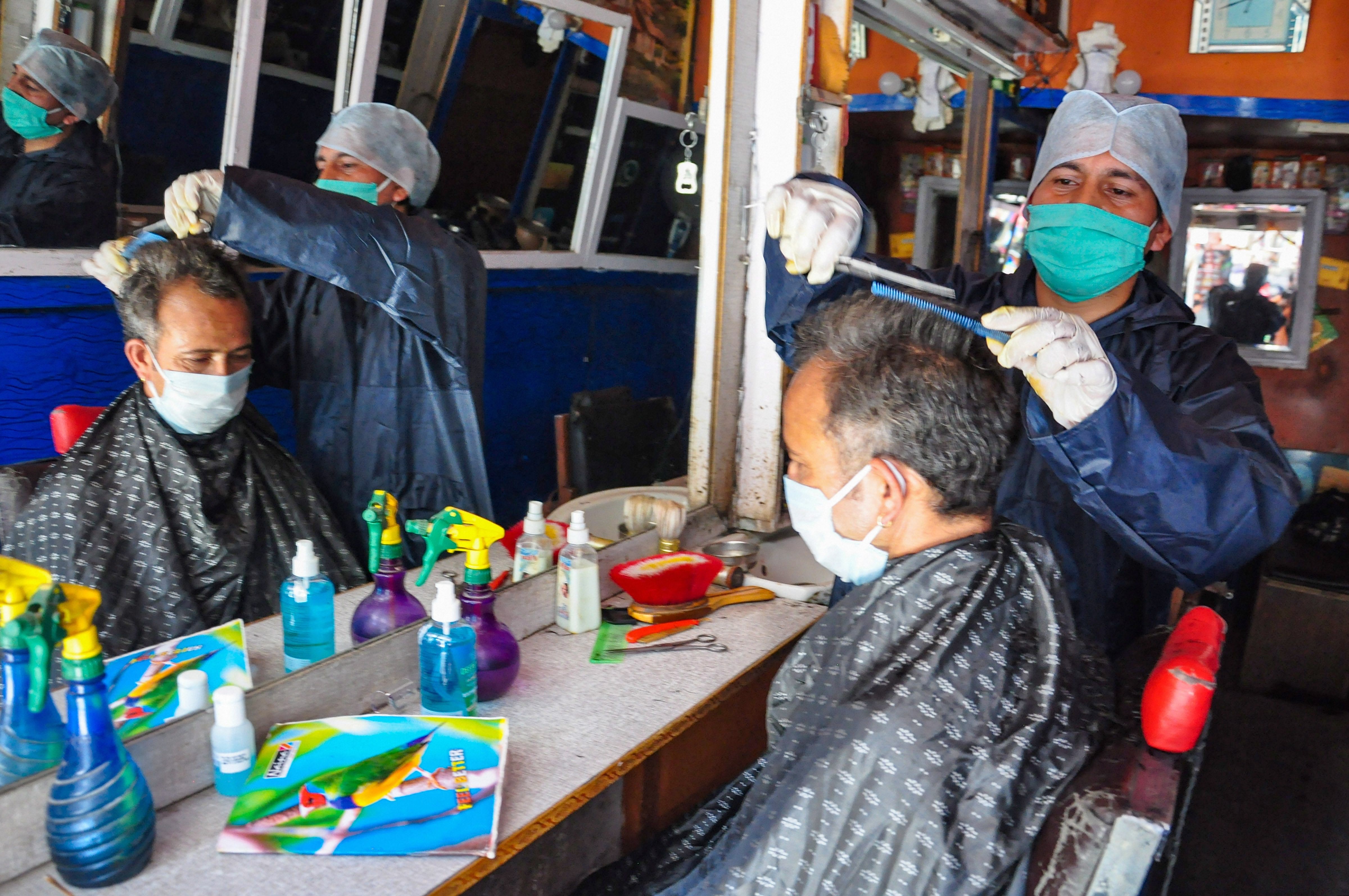  barber wearing a face mask attends to a customer at his salon, during the ongoing COVID-19 lockdown, in Kullu. (PTI Photo)