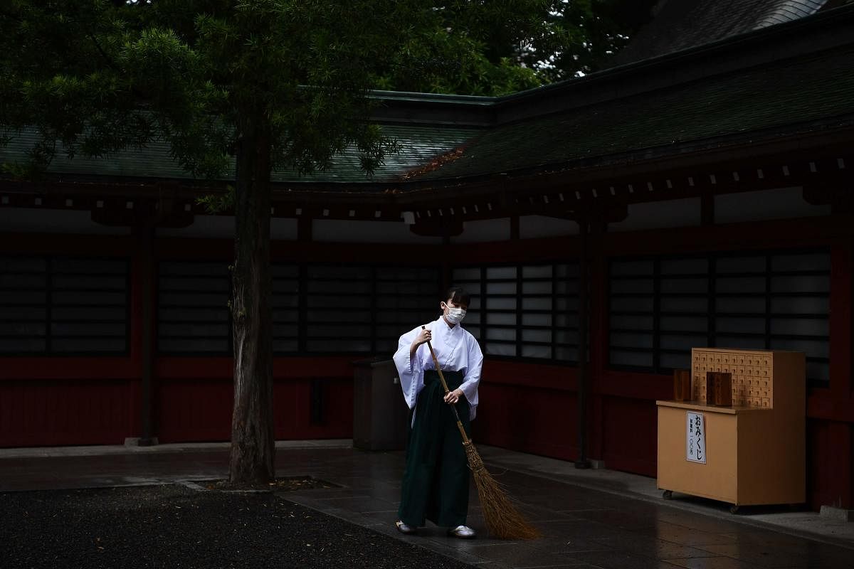 A "miko", shrine maiden or a supplementary priestess, sweeps the ground in the Okunitama shinto shrine in Fuchu, Tokyo prefecture on June 1, 2020. Credit: AFP Photo
