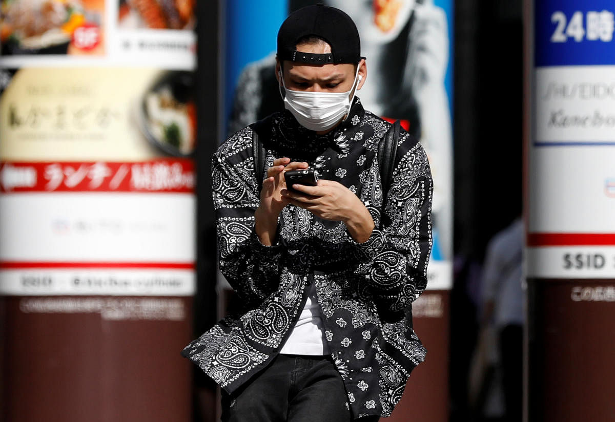 A man wearing a protective face mask uses his mobile phone in Akihabara district, following the coronavirus disease (COVID-19) outbreak in Tokyo. Reuters