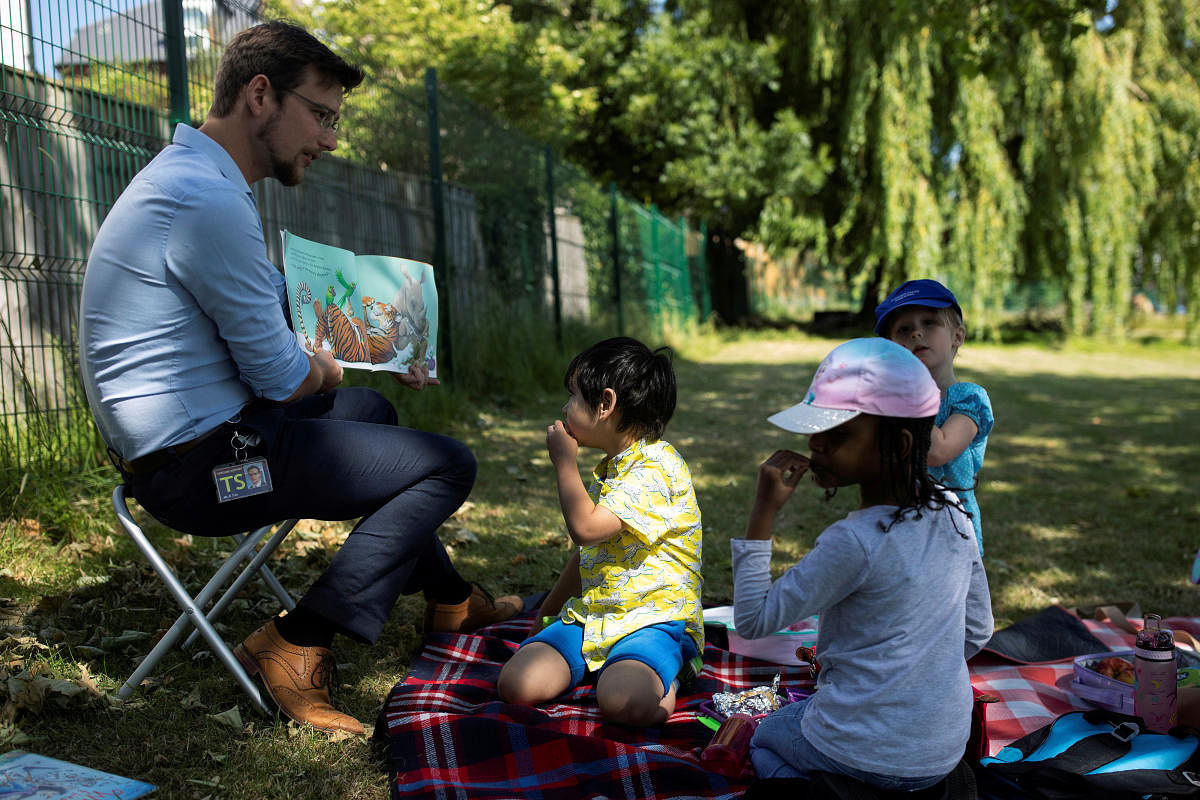 A teacher reads children a story in the grounds of St Dunstan's College junior school as some schools re-open following the outbreak of the coronavirus disease (COVID-19) in London. Reuters