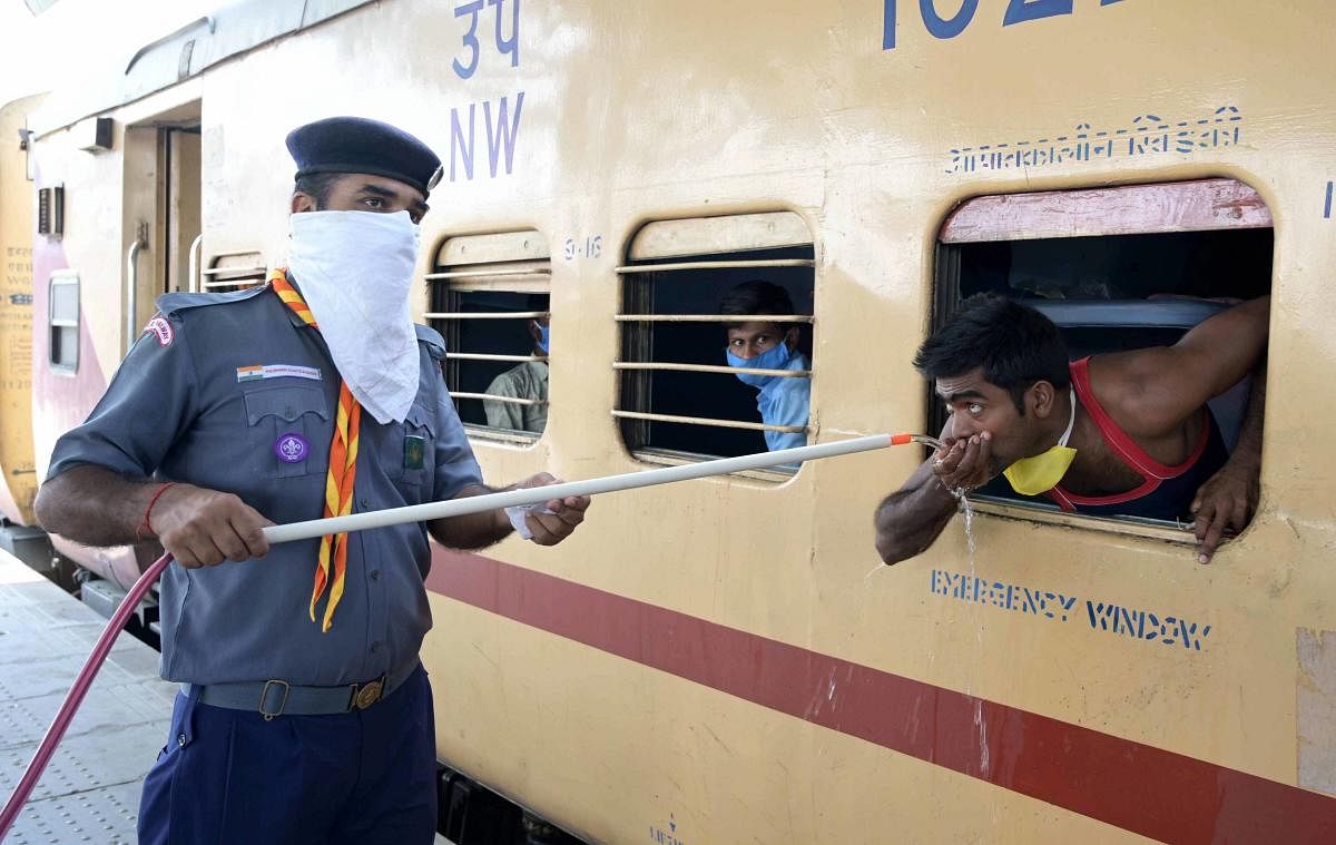  A cadet of Scouts & Guides provide drinking water to the migrants traveling in a Shramik Special train to their native places, during ongoing COVID-19 lockdown, at Prayagraj Railway Station,Thursday, May 28, 2020. (PTI Photo)