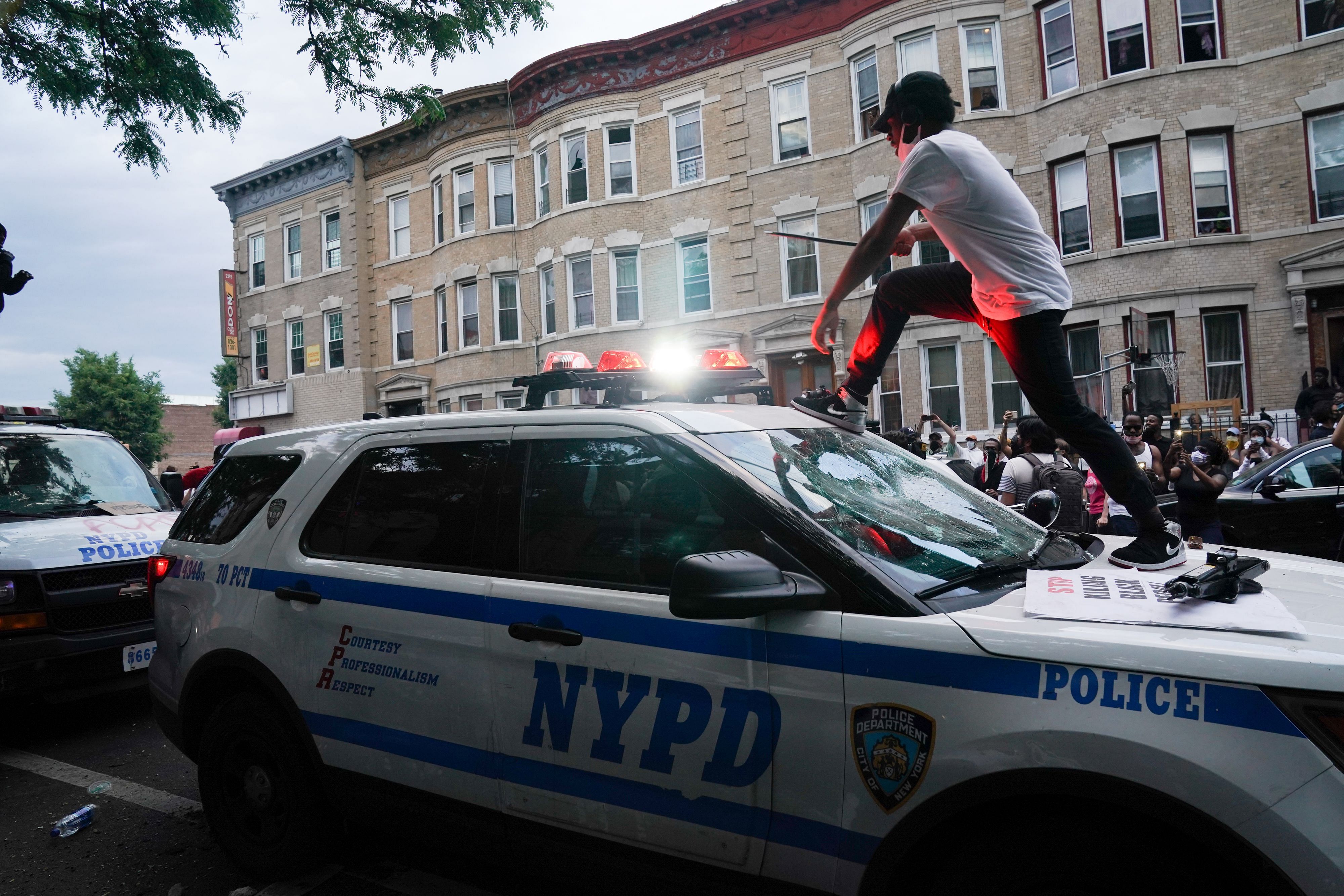 A protester jumps on an NYPD police SUV during a demonstration against the killing of George Floyd by Minneapolis police on Memorial Day on May 30, 2020. (Credit: AFP Photo)