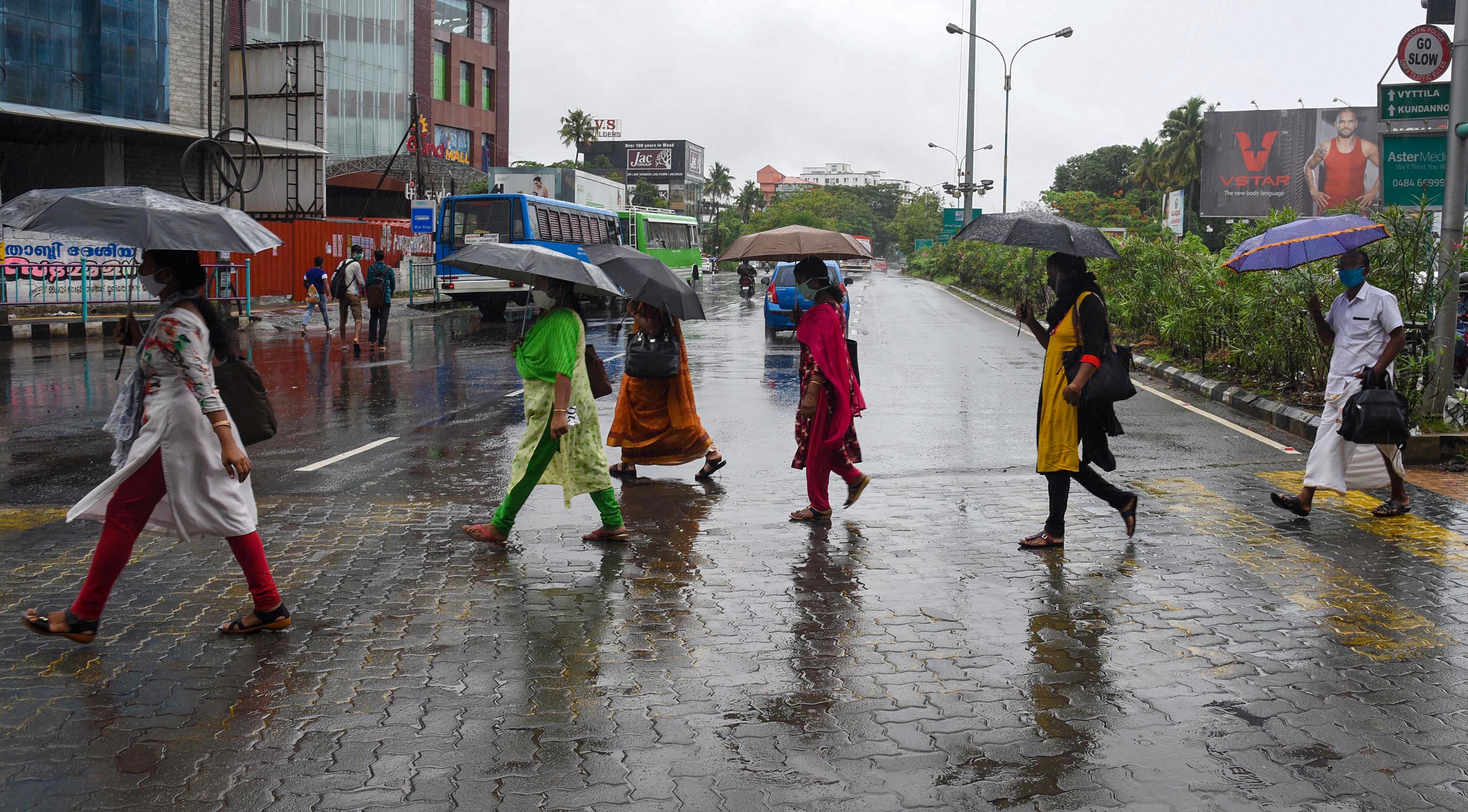 People under umbrellas walk on a road during rain as monsoon has hit Kerala to embark on the rainy season in the country amid coronavirus pandemic, in Kochi, Tuesday, June 2, 2020. (PTI Photo)