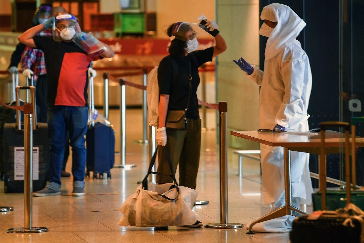 A health worker wearing Personal Protective Equipment (PPE) interacts with an arriving passengers at the Chhatrapati Shivaji Maharaj International Airport (CSMIA) after domestic flights resumed, in Mumbai on May 28, 2020. Credit: AFP Photo
