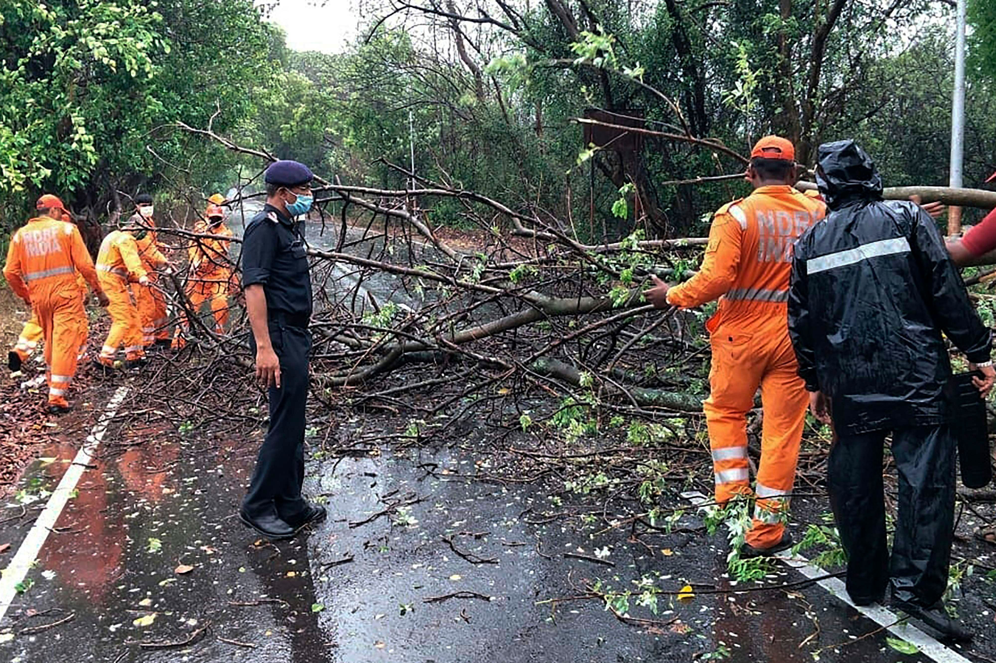  NDRF personnel clearing fallen trees from a road in Alibag town of Raigad district following cyclone Nisarga landfall in India's western coast. - Cyclone Nisarga ripped roofs off homes in a coastal town near Mumbai on May 3 after officials ordered offices and factories to shut and told people to stay home, reversing a move to ease a coronavirus lockdown in the Indian megacity. Mumbai and its surrounds are usually sheltered from cyclones -- the last severe storm to hit the city was in 1948 -- but authorities have evacuated at least 100,000 people from flood-prone areas in the states of Maharashtra and Gujarat. (Photo by National Disaster Response Force (NDRF) / AFP)