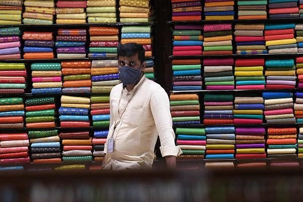A sales person wearing a facemask waits for customers at a textile garment shop after the government eased a nationwide lockdown imposed as a preventive measure against the COVID-19 coronavirus, in Chennai on June 1, 2020. (Credit: AFP Photo)