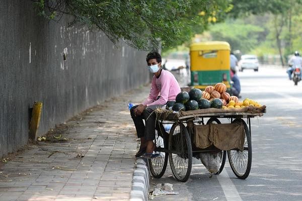 A fruit vendor waits for costumers along a road after the government eased a nationwide lockdown imposed as a preventive measure against the COVID-19 coronavirus, in New Delhi on May 31, 2020. (Credit: AFP Photo)