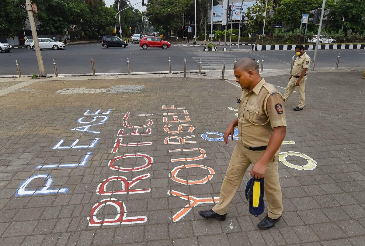 Mumbai: Police personnel walk past a painted message that reads 'Please Protect Yourself And Others' at Marine Drive promenade after the government permits walking and jogging activities, during the ongoing COVID-19 lockdown, in Mumbai, Tuesday, June 2, 2