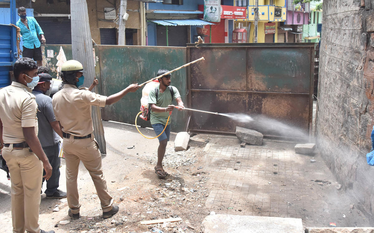 A health worker sprays disinfectant in Chalavadipalya of Bengaluru on Wednesday. DH Photo