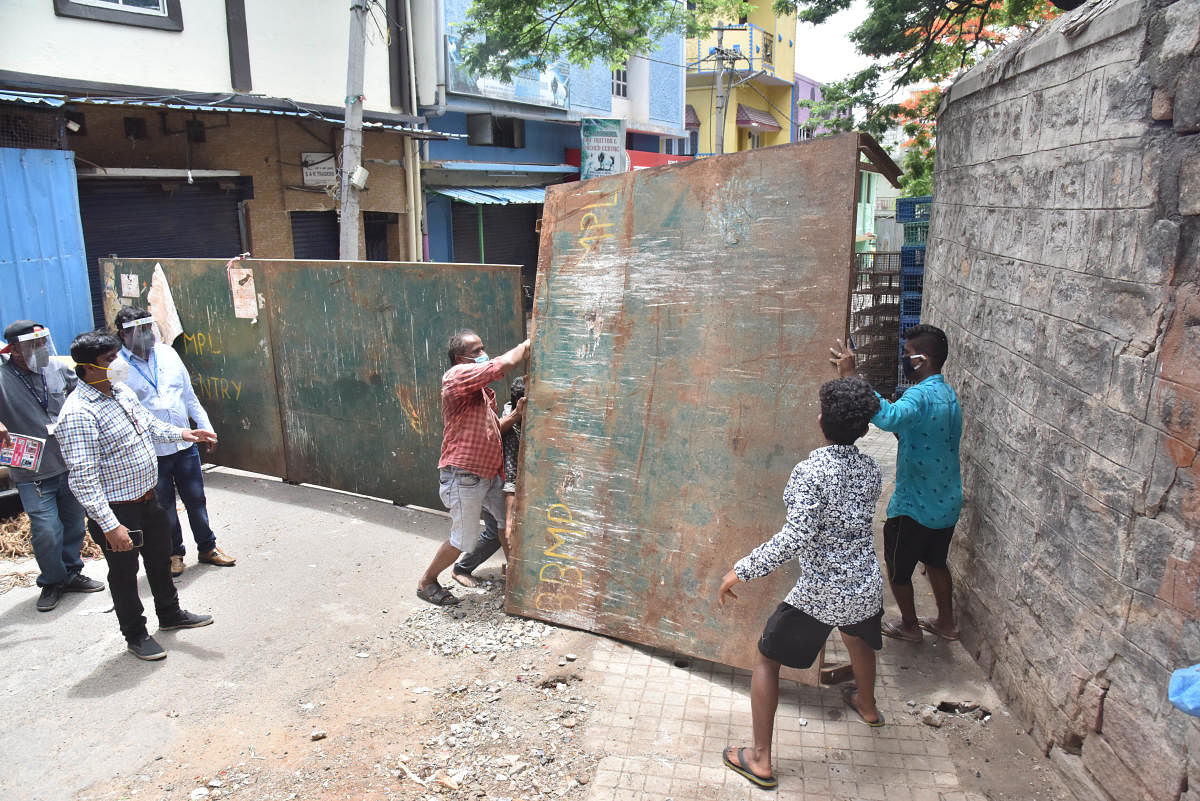 BBMP workers seal down a street in Old Pension Mohalla, Chalavadi Palya, on Wednesday. SP Road, the busy electronics hub, continued to draw customers despite being sealed down. DH PHOTOs/JANARDHAN B K and M S MANJUNATH