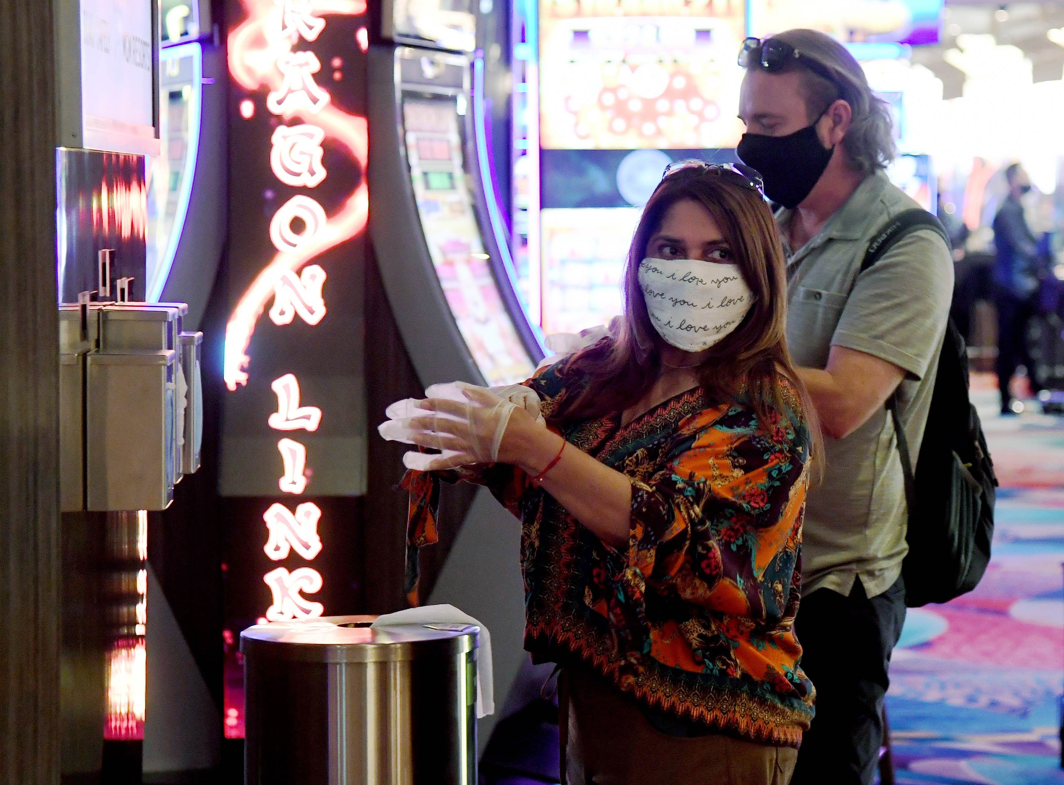 Guests take complimentary gloves from the side of a new hand-washing station on the gaming floor that also offers masks and wipes at Bellagio Resort & Casino on the Las Vegas Strip after the property opened for the first time since being closed on March 17 because of the coronavirus. (AFP Photo)