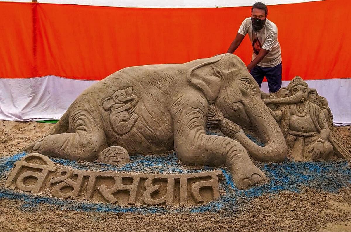 An artist gives finishing touch to a sand sculpture representing the recently killed wild pregnant elephant of Kerala, on the eve of World Environment Day, in Chapra. PTI