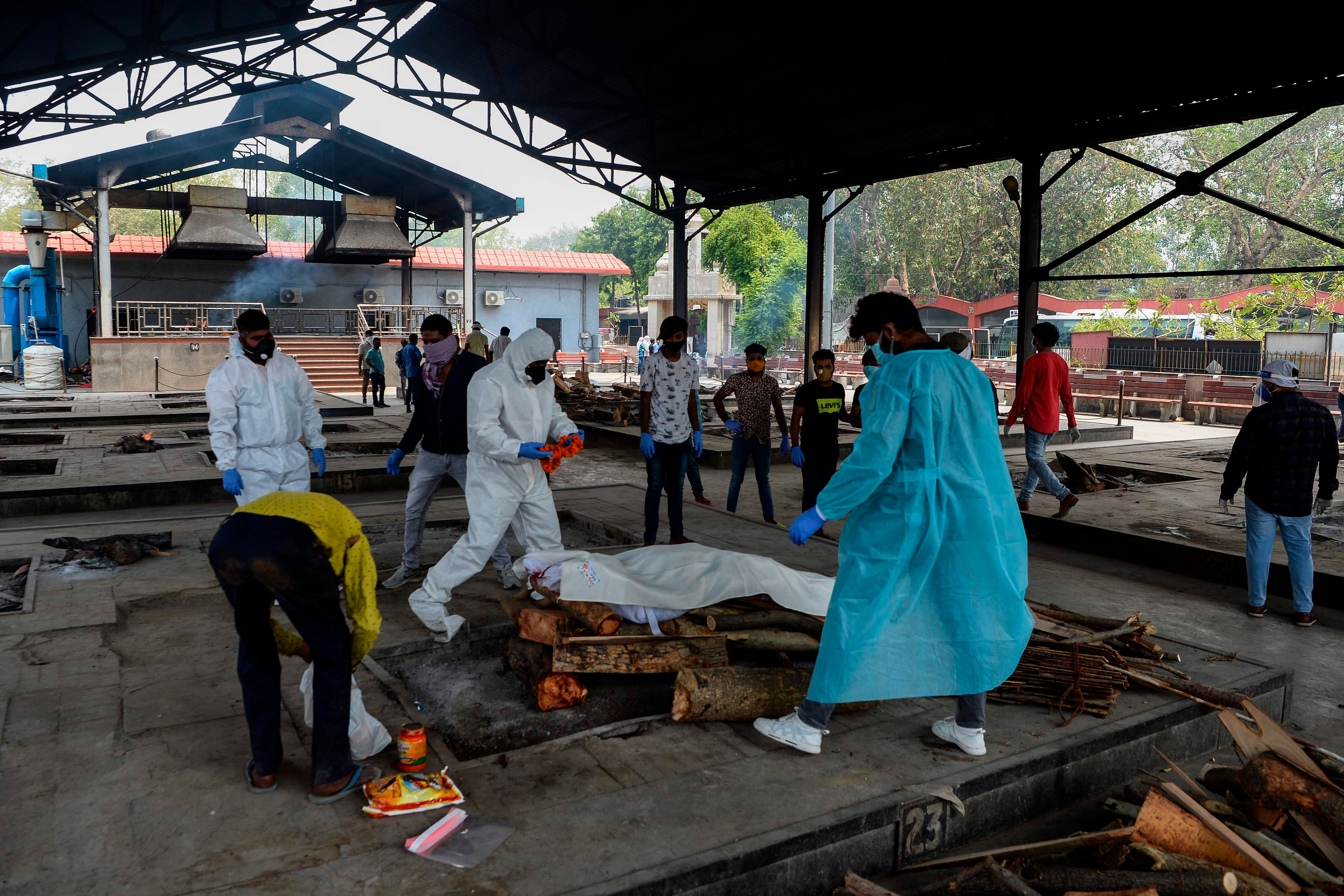 Workers and relatives wearing Personal Protective Equipment (PPE) prepare the body of a person who died from the COVID-19. (AFP Photo)