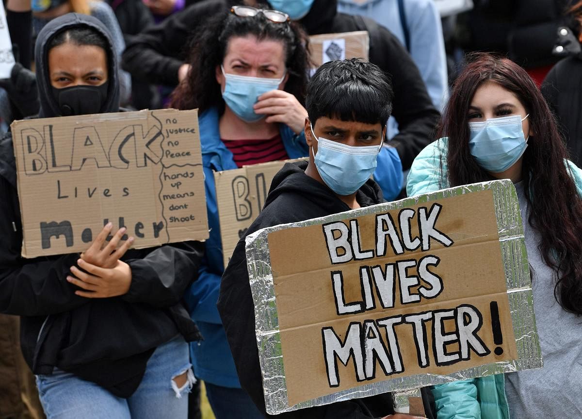 Protesters, some wearing PPE (personal protective equipment), of a face mask as a precautionary measure against COVID-19, hold placards as they attend a demonstration in Manchester, northern England, on June 6, 2020, to show solidarity with the Black Lives Matter movement in the wake of the killing of George Floyd, an unarmed black man who died after a police officer knelt on his neck in Minneapolis. Credit/AFP Photo