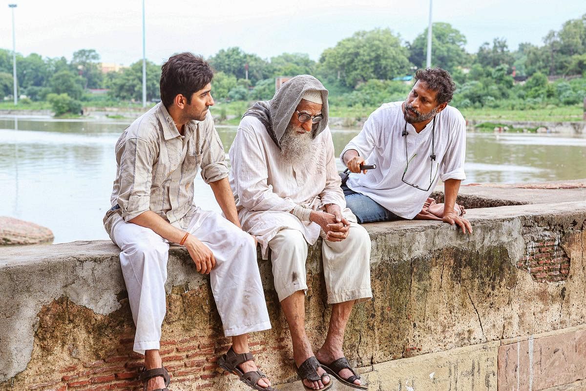 In this undated photo Bollywood actors Amitabh Bachchan and Ayushmann Khurrana with film director Shoojit Sircar during the shoot of their film 'Gulabo Sitabo'. (PTI Photo)