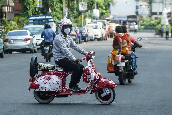 Painter Tarak Das (L) rides his coronavirus-themed painted scooter after the government eased a nationwide lockdown imposed as a preventive measure against the COVID-19 coronavirus, in Kolkata on June 4, 2020. (Credit: AFP Photo)