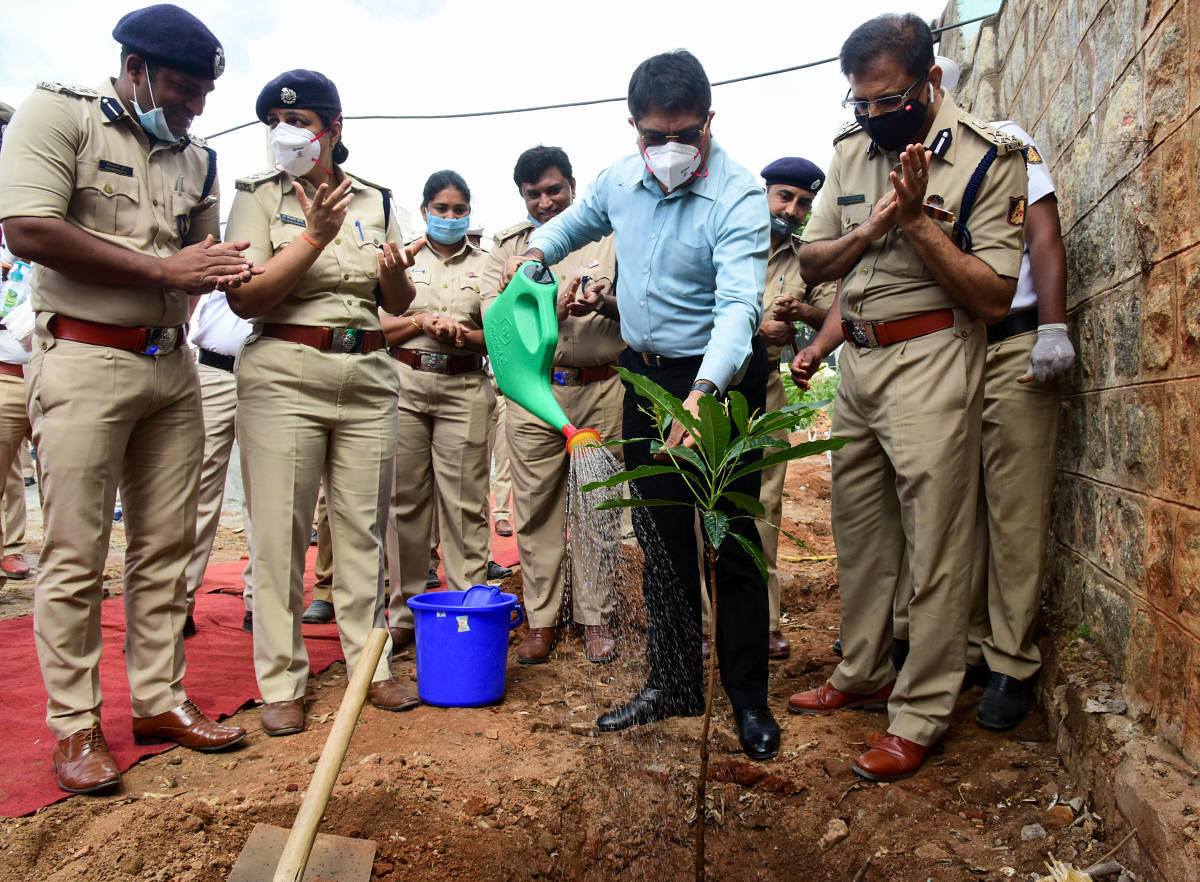 Police officials plant a mango sapling at Jakkarayanakere ground near Malleswaram on Friday. DH Photo/B H Shivakumar