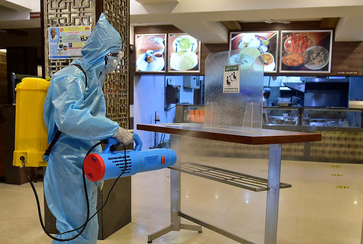 A staffer in protective gear sprays disinfect at a hotel in Bengaluru on Saturday. DH Photo/Ranju P