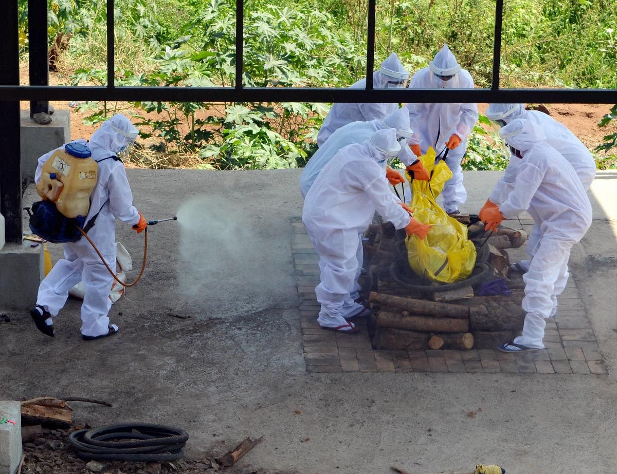 Municipal workers wearing protective suits prepare to cremate the body of a COVID-19 patient, during the ongoing nationwide lockdown, in Karad, Saturday, May 30, 2020. Credit/PTI Photo