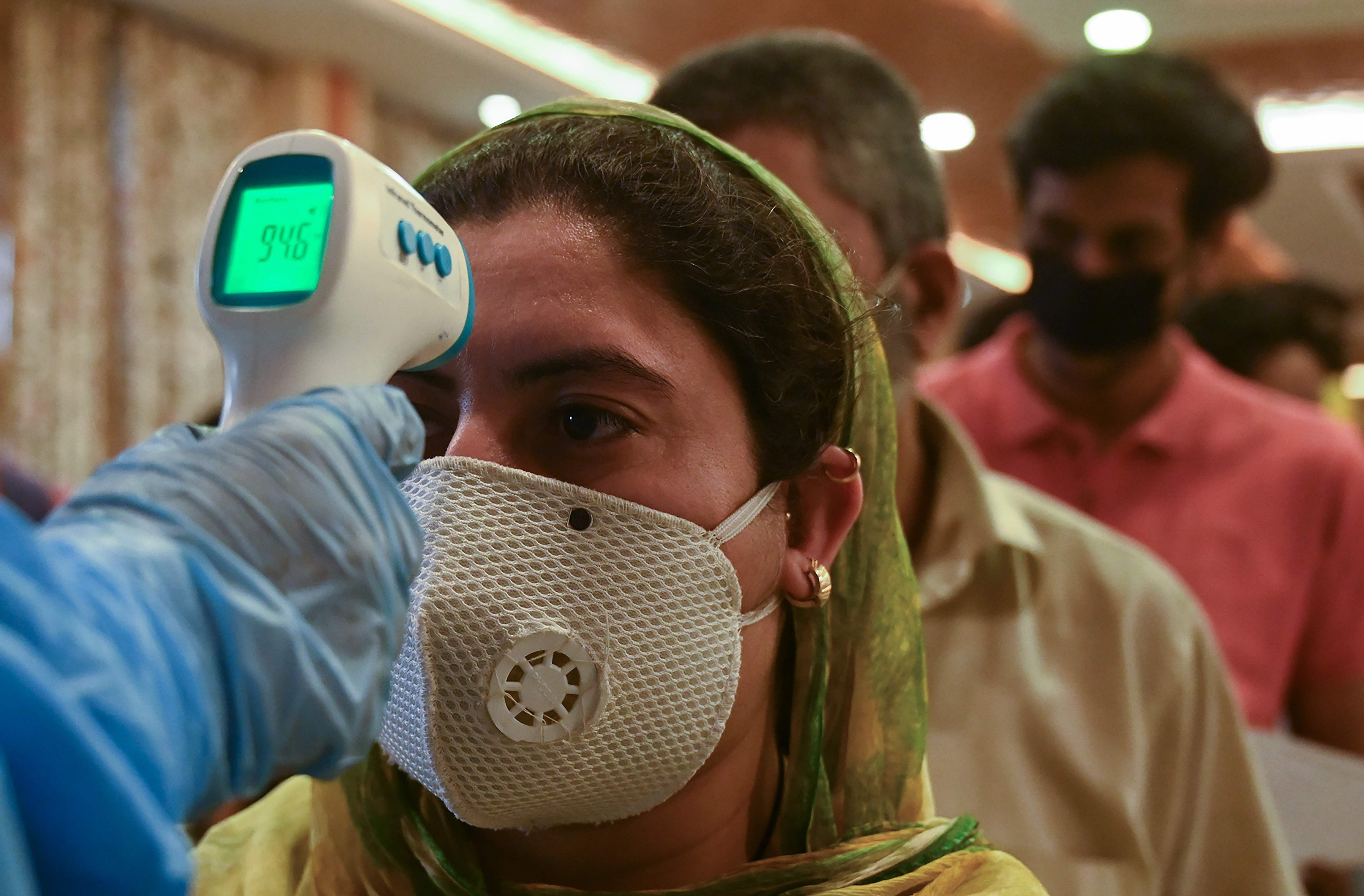 A doctor checks the body temperature of migrant workers and business owners upon returning from Goa after the government eased a nationwide lockdown as a preventive measures against the spread of the COVID-19 coronavirus. Credit: AFP Photo