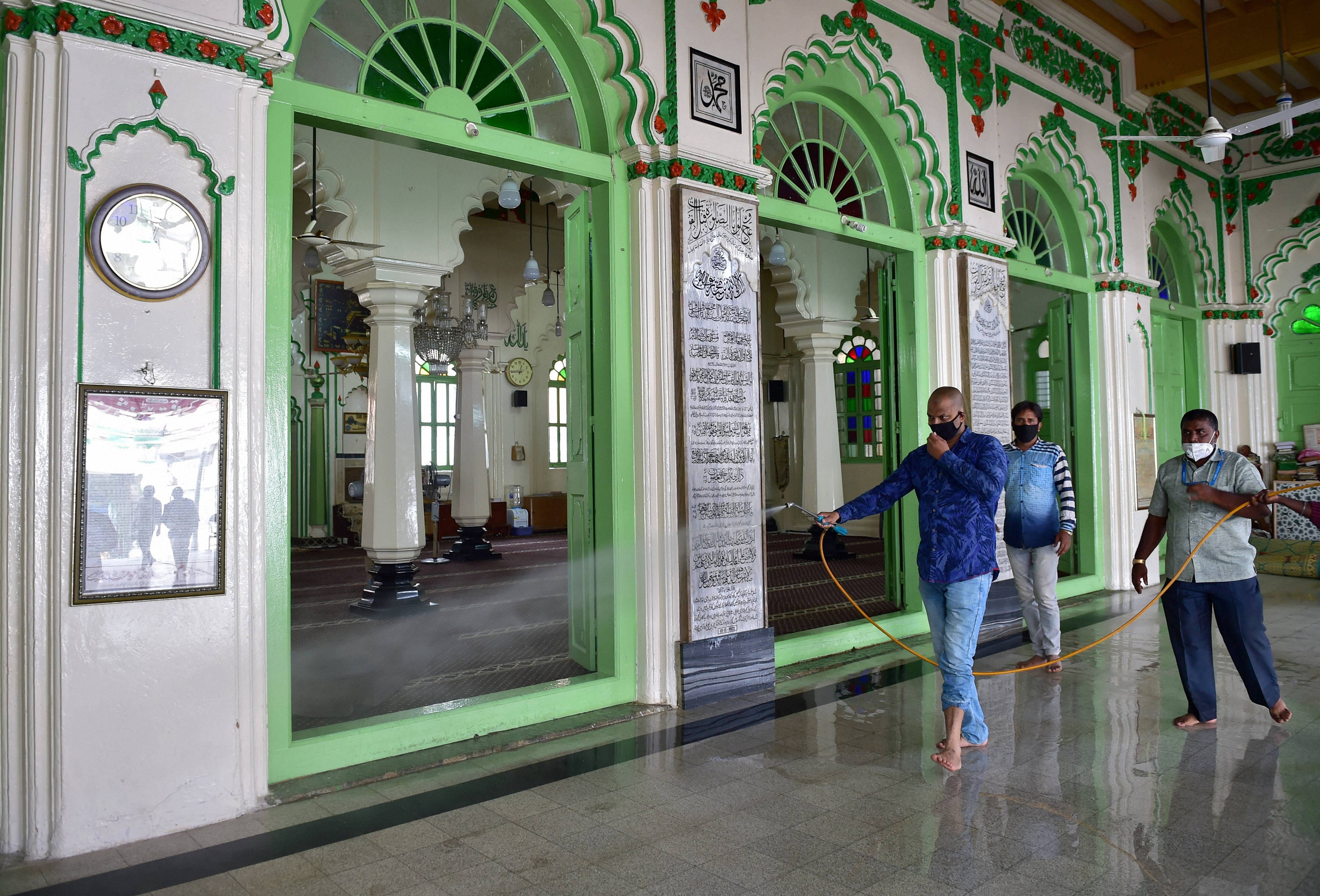 A worker sprays disinfectant at a mosque ahead of its re-opening, during the ongoing COVID-19 lockdown, in Bengaluru. Credit: PTI Photo